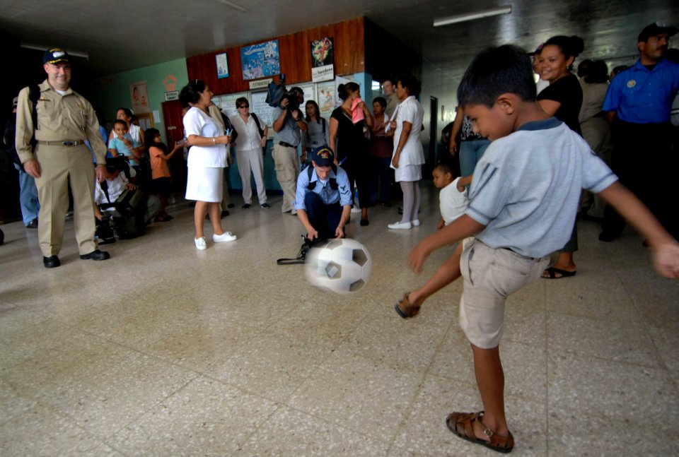 US Navy 070719-N-0194K-201 A local boy passes a soccer ball to Capt. Bob Kapcio, mission commander aboard the Military Sealift Command hospital ship USNS Comfort (T-AH 20), during a tour of Jose Schendal Health Center