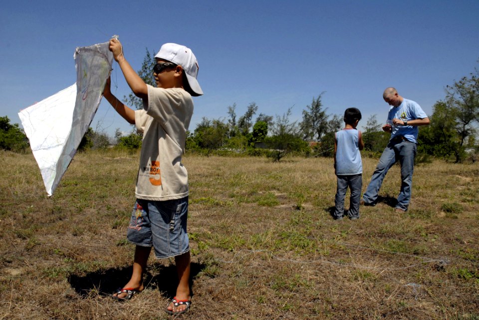 US Navy 070719-N-4267W-042 A Sailor assigned to USS Peleliu (LHA 5) helps construct a kite for two Vietnamese children at the Hoi Mai Orphanage during Pacific Partnership 2007