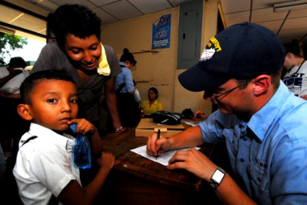 US Navy 070720-N-8704K-089 Hospitalman Wesley Williams, attached to Military Sealift Command hospital ship USNS Comfort (T-AH 20), checks in Johanna Mendosa and her son to the 15 de Julio Health Care Clinic