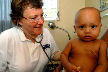 US Navy 070720-N-8704K-109 Project Hope volunteer Terry Martaus, attached to Military Sealift Command hospital ship USNS Comfort (T-AH 20), provides medical care for a one-year-old child at the 15 de Julio Health Care Center