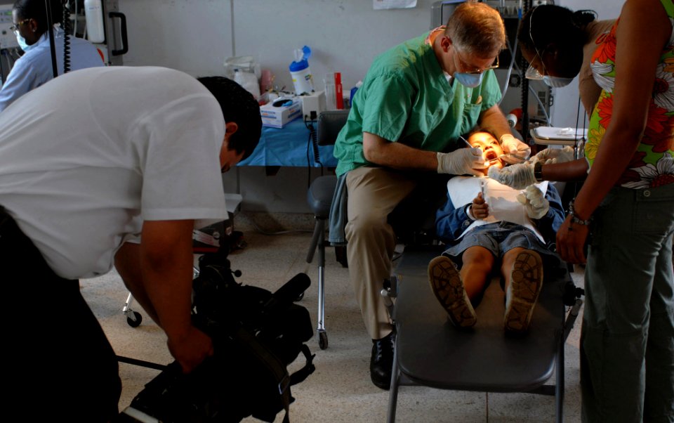 US Navy 070723-N-7088A-005 Edgard Aguilar, from Managua Channel 12, videotapes a patient receiving dental care from Capt. Joseph Rusz at the El Realejo Health Care Center, where medical personnel attached to Military Sealift Co