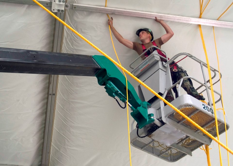 US Navy 070719-N-5253W-003 Construction Electrician Constructionman John Kinghorn, of Naval Mobile Construction Battalion Seven (NMCB 7), runs lines through the frame of a tension fabric structure at the Ikego Housing Compound