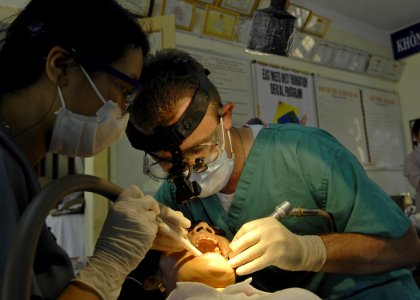 US Navy 070724-N-4954I-148 Lt. Kevin Haveman, with 3rd Medical Battalion, cleans teeth with a dental assistant from the East Meets West Dental Program at Nai Hiem Dong Medical Station photo