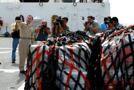 US Navy 070725-N-0194K-048 Capt. Bob Kapcio, mission commander aboard Military Sealift Command hospital ship USNS Comfort (T-AH 20), shows local media from El Salvador pallets of medical supplies destined for their country
