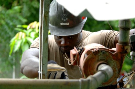 US Navy 070721-N-0194K-113 Utilitiesman 2nd Class Jason Burton, with Construction Battalion Maintenance Unit (CBMU) 202, works to free and remove an old water pump at the 15 de Julio Health Care Center