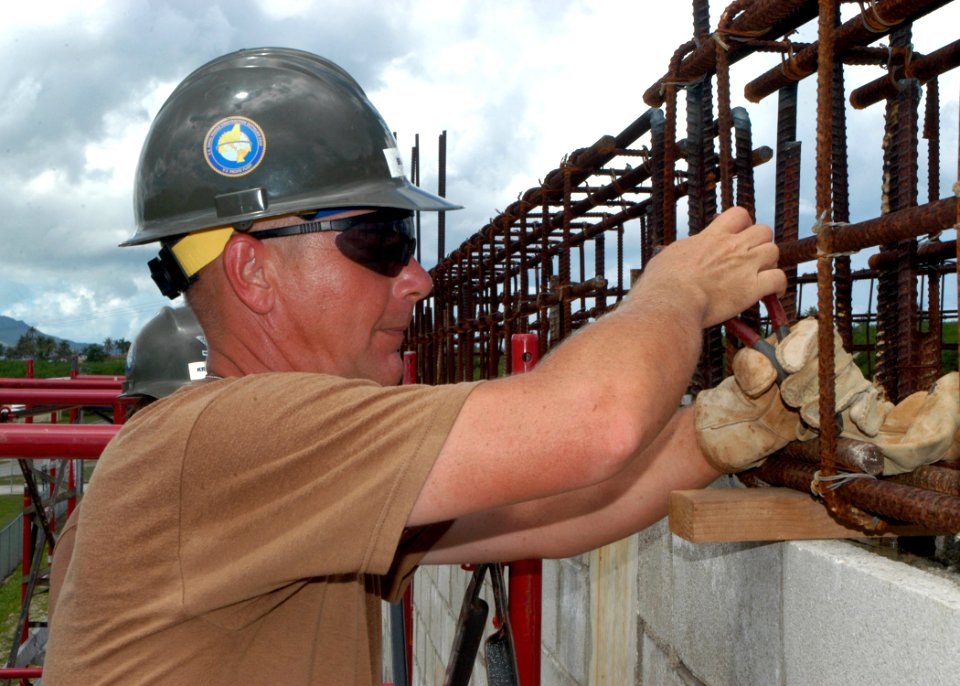 US Navy 070723-F-8678B-072 Builder 1st Class Phillip Brewer ties a reinforcement bar into the concrete roof of the mechanical shop project at Orote Point Quarry