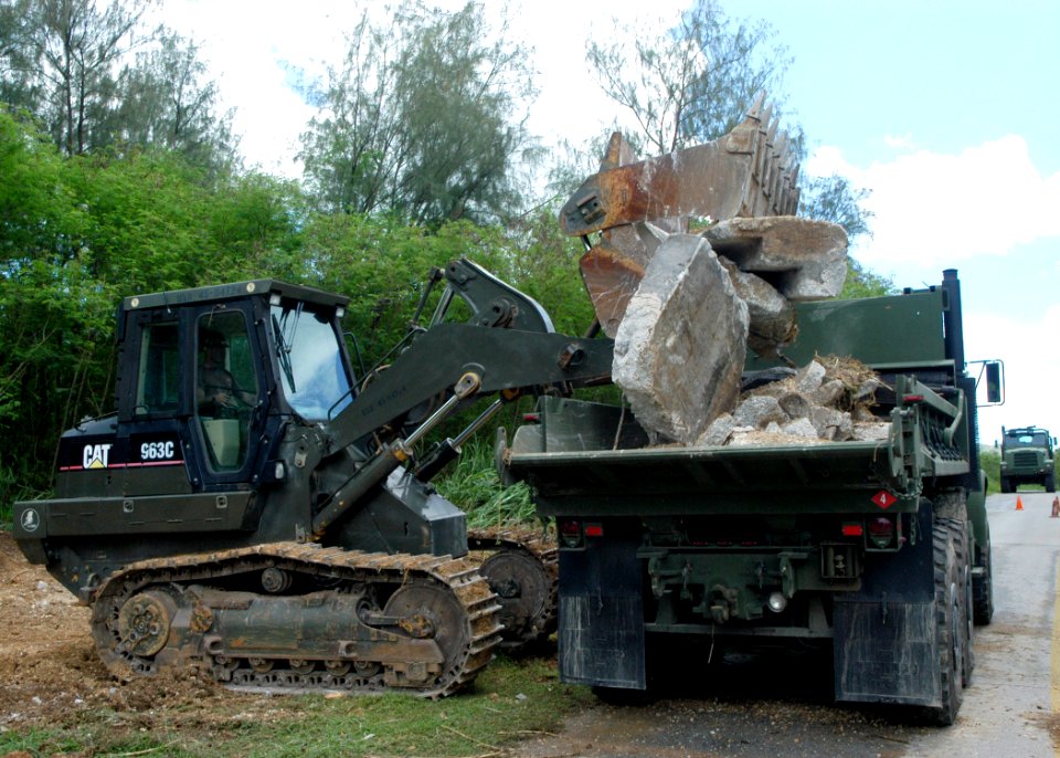 US Navy 070723-F-8678B-059 Equipment Operator 1st Class Lawrence A. Zeigler operates a track-type loader to load debris into a Medium Tactical Vehicle Replacement dump truck following demolition of a concrete wall as part of a