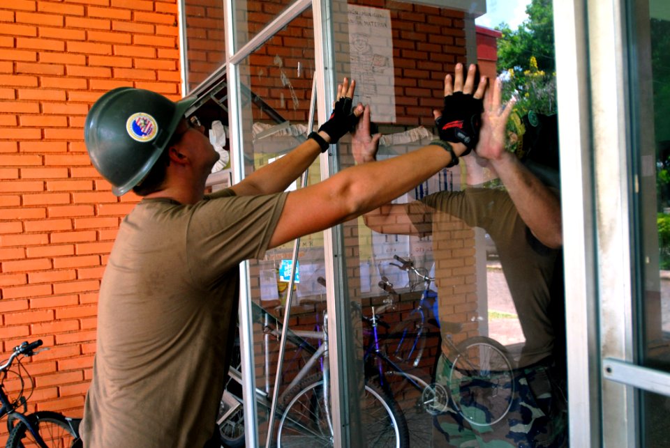 US Navy 070724-N-4238B-025 Sailors attached to Military Sealift Command hospital ship USNS Comfort (T-AH 20), lift a pane of glass into place at Jose Schendal Health Center