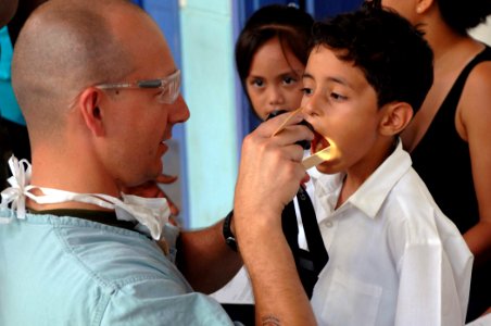 US Navy 070723-N-7088A-007 Canadian Forces Capt. Tim Barter inspects Luis Duilio's teeth prior to a fluoride treatment at the El Realejo Health Care Center, where medical personnel attached to Military Sealift Command hospital photo