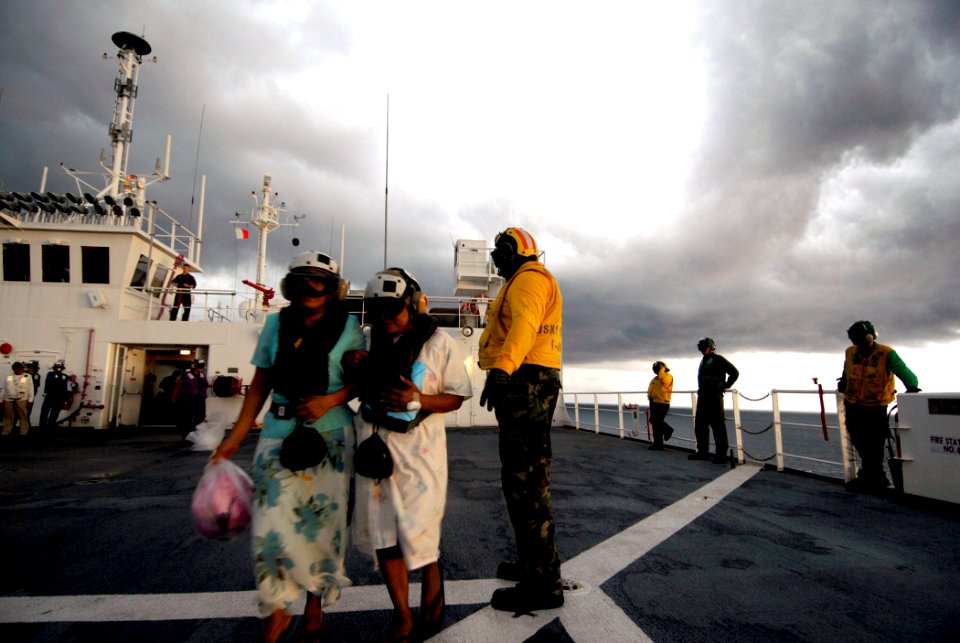 US Navy 070724-N-6081J-071 Aviation Boatswain's Mate (Handling) 1st Class Kevin Jasey directs patients on a safe path toward an MH-60S Seahawk on the flight deck of Military Sealift Command Naval hospital ship USNS Comfor