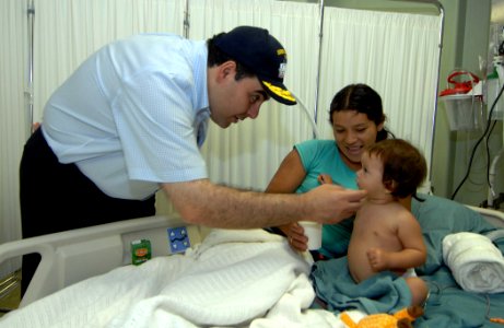 US Navy 070727-N-0194K-052 President of El Salvador, Elias Saca, shares a moment with a young child and her mother aboard the Military Sealift Command hospital ship USNS Comfort (T-AH 20)