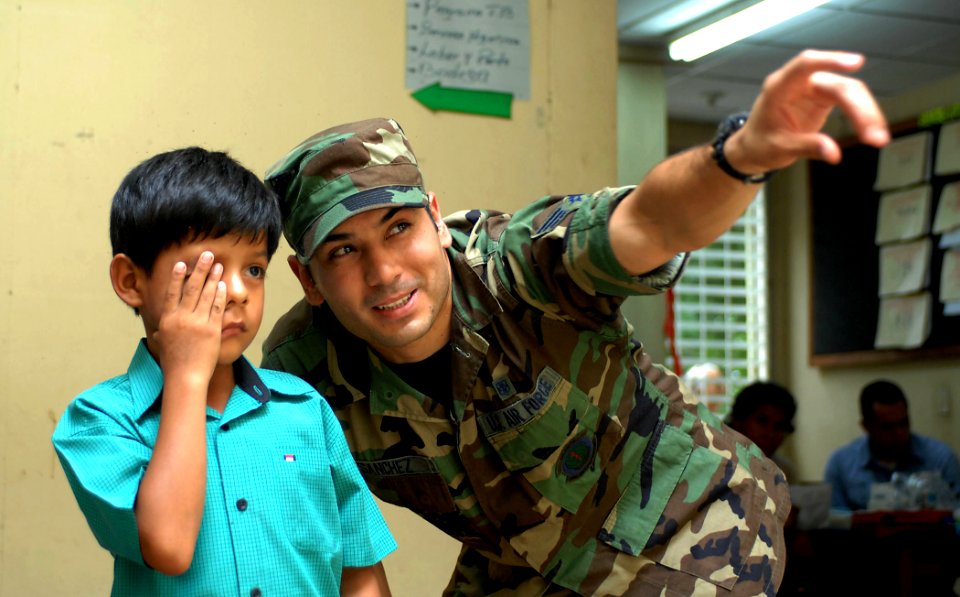 US Navy 070721-N-0194K-187 Air Force Airman Sebastian Sanchez, a laboratory technician attached to Military Sealift Command hospital ship USNS Comfort (T-AH 20), assists an eight-year-old child during an eye examination at the