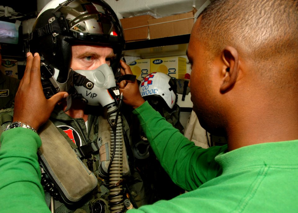 US Navy 070722-N-5928K-003 Aircrew Survival Equipmentman 1st Class Paul-Brian Raghoo assists British Royal Air Force Air Marshall, Sir Graham Anthony Miller, with his helmet prior to launching from the flight deck