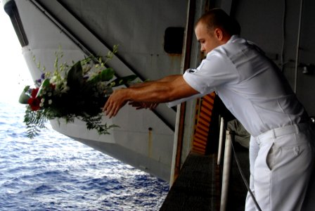 US Navy 070724-N-8923M-121 Aviation Machinist's Mate 3rd Class Robert Scott, from the Raging Bulls of Strike Fighter Squadron (VFA) 37, tosses a wreath overboard in honor of Aviation Ordnanceman 3rd Class Adam Cline