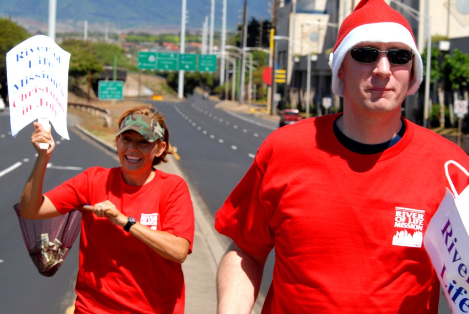US Navy 070725-N-4965F-003 Personnel Specialist 1st Class Robert Whittle and Master-at-Arms 1st Class Jinine Green spread Christmas cheer to passing motorists as part of a volunteer project and fundraiser for the River of Life