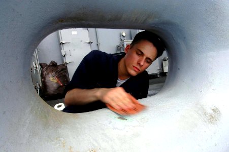US Navy 070727-N-7883G-008 Seaman Dana Fitch, of West Palm Beach, Fla., sands a chock on the fantail aboard USS Kitty Hawk (CV 63)