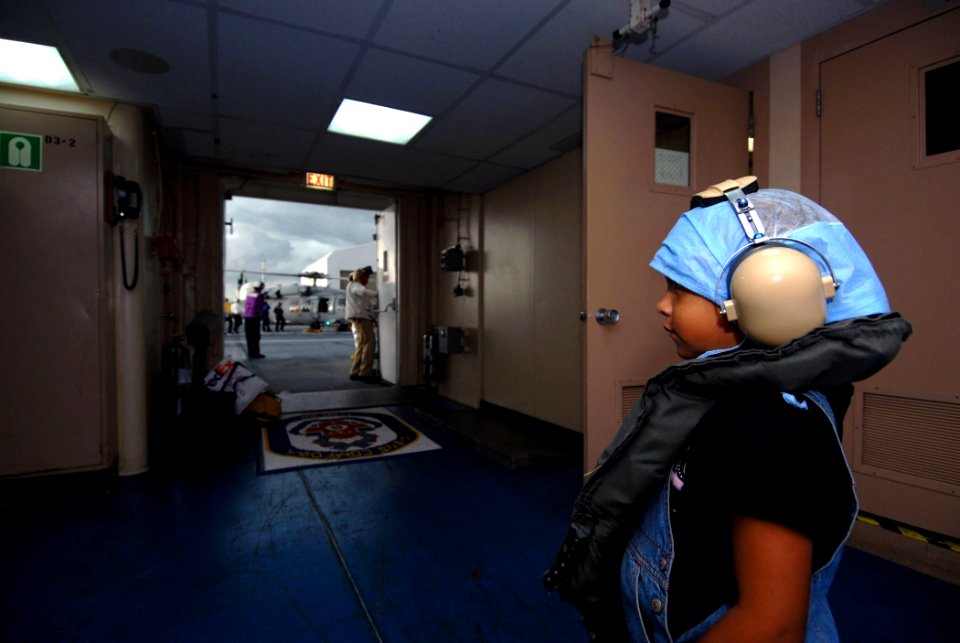 US Navy 070724-N-6081J-020 A five-year-old patient aboard Military Sealift Command (MSC) hospital ship USNS Comfort (T-AH 20), watches an MH-60S Seahawk land on the flight deck of Comfort as she waits for a return flight to her