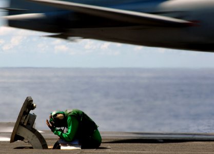 US Navy 070726-N-8923M-156 A phone talker ducks his head as an EA-6B Prowler, attached to the Zappers of Tactical Electronic Warfare Squadron (VAQ) 130, is launched from the waist of the flight deck aboard Nimitz-class aircraft