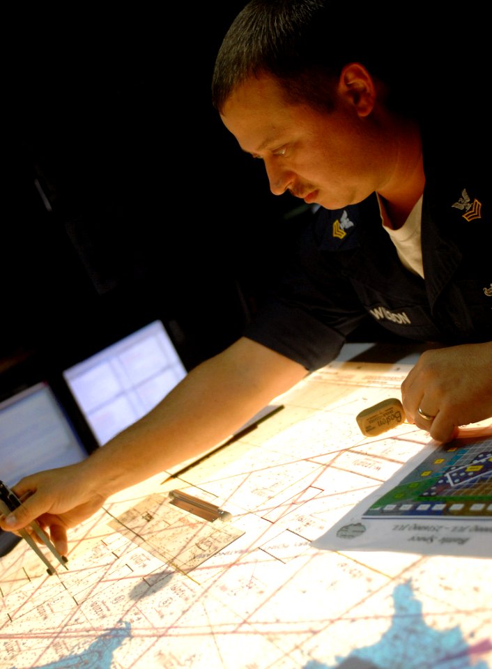 US Navy 070728-N-8923M-039 Operations Specialist 1st Class Larry Wilson calculates positions on submarine charts in Combat Direction Center (CDC) aboard the Nimitz-class aircraft carrier USS Harry S. Truman (CVN 75)