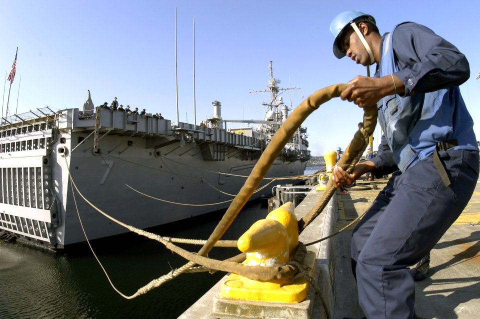 US Navy 070730-N-3390M-001 Seaman Rodney Walls, of guided-missile destroyer USS Shoup (DDG 86), dips the eye of the aft mooring line of amphibious transport dock USS Cleveland (LPD 7) to secure the ship to the pier during the s