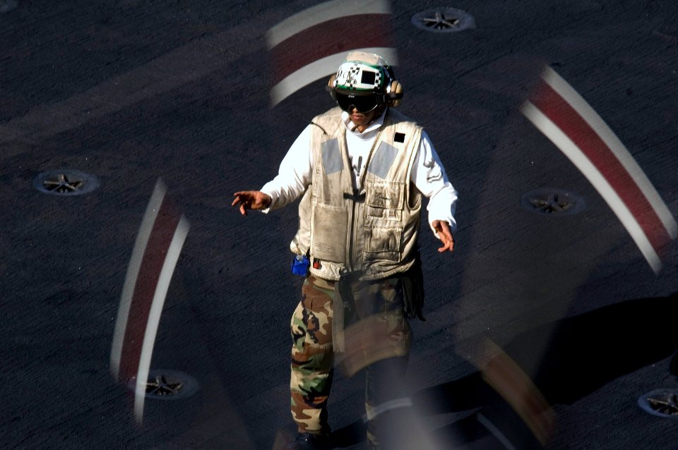 US Navy 070728-N-5387K-055 Aviation Structural Mechanic 2nd Class John Mayo, 25, from Los Angeles, directs an E-2C Hawkeye aboard the USS Kitty Hawk (CV 63) flight deck