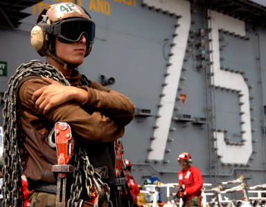 US Navy 070728-N-8923M-082 A plane captain assigned to the Gunslingers of Strike Fighter Squadron (VFA) 105, carries chocks and chains while waiting for aircraft to land during flight operations aboard the Nimitz-class aircraft