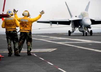 US Navy 070729-N-7981E-168 An aircraft director and his trainee under instruction signal to the pilot of an F-A-18F Super Hornet assigned to the Bounty Hunters of Strike Fighter Squadron (VFA) 2 as the aircraft makes an arreste