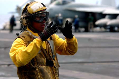 US Navy 070804-N-7883G-060 Aviation Boatswain's Mate (Handling) Airman Johnkeith Elopre, directs aircraft during flight operations aboard USS Kitty Hawk (CV 63)