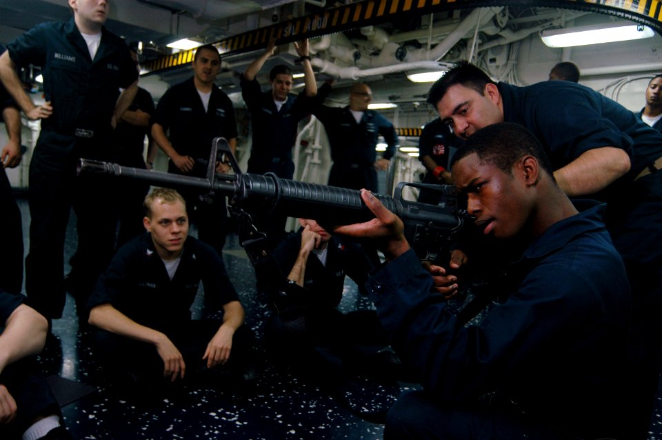 US Navy 070728-N-3136P-045 Chief Gunner's Mate Walton Ciferri, instructs Aviation Ordnanceman Airman Robert Hunter on M-16 machine gun handling procedures during weapons familiarization training aboard USS Kitty Hawk (CV 63)