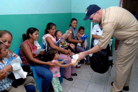 US Navy 070728-N-7088A-224 Senior Chief Operations Specialist Gene Demers, attached to the Military Sealift Command hospital ship USNS Comfort (T-AH 20), hands out teddy bears to children at Unidad de Salud Health Center in Aca