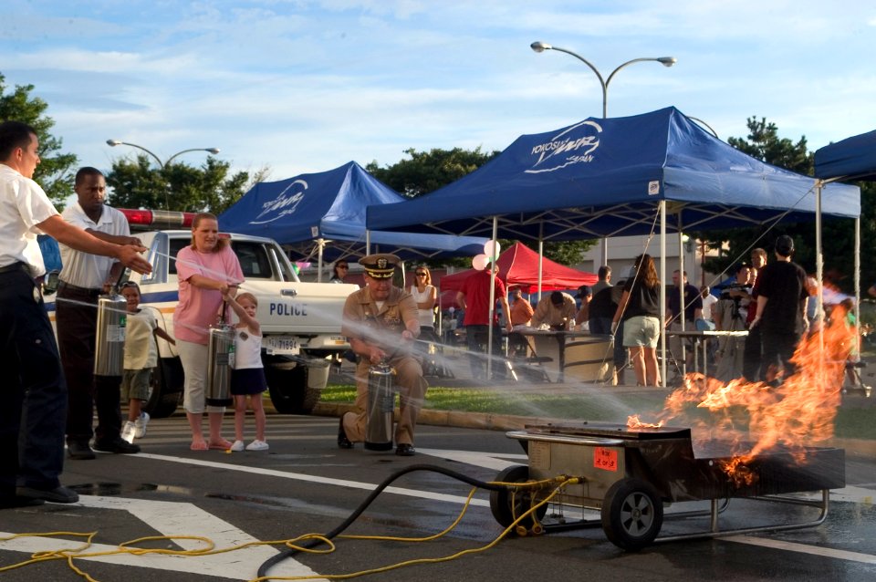 US Navy 070807-N-0483B-003 Commanding Officer of Fleet Activities Yokosuka, Capt. Daniel L. Weed and members of the community learn how to properly extinguish a fire during the 24th Annual National Night Out photo