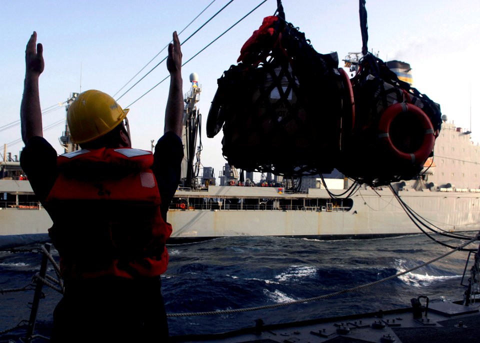 US Navy 070804-N-8132M-098 A Sailor aboard the guided missile destroyer Arleigh Burke (DDG 51) signals the supplies are over the deck of the receiving station during a replenishment at-sea