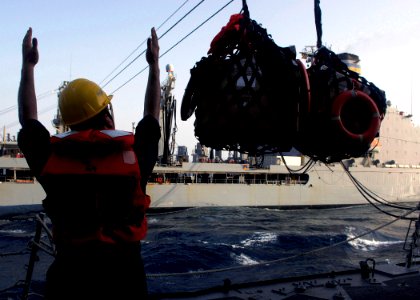 US Navy 070804-N-8132M-098 A Sailor aboard the guided missile destroyer Arleigh Burke (DDG 51) signals the supplies are over the deck of the receiving station during a replenishment at-sea