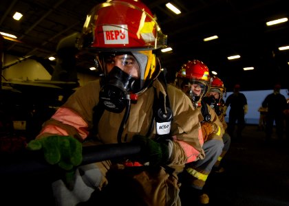 US Navy 070804-N-7981E-190 Members of a repair locker hose team advance on a simulated fire in the hangar bay of Nimitz-class aircraft carrier USS Abraham Lincoln (CVN 72), during a General Quarters (GQ) drill photo
