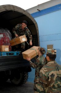 US Navy 070806-N-7088A-163 U.S. Air National Guard Senior Airman Andrew Hendrick, attached to the Military Sealift Command (MSC) hospital ship USNS Comfort (T-AH 20) hands boxes of supplies to Air Force Staff Sgt. Scott Super photo