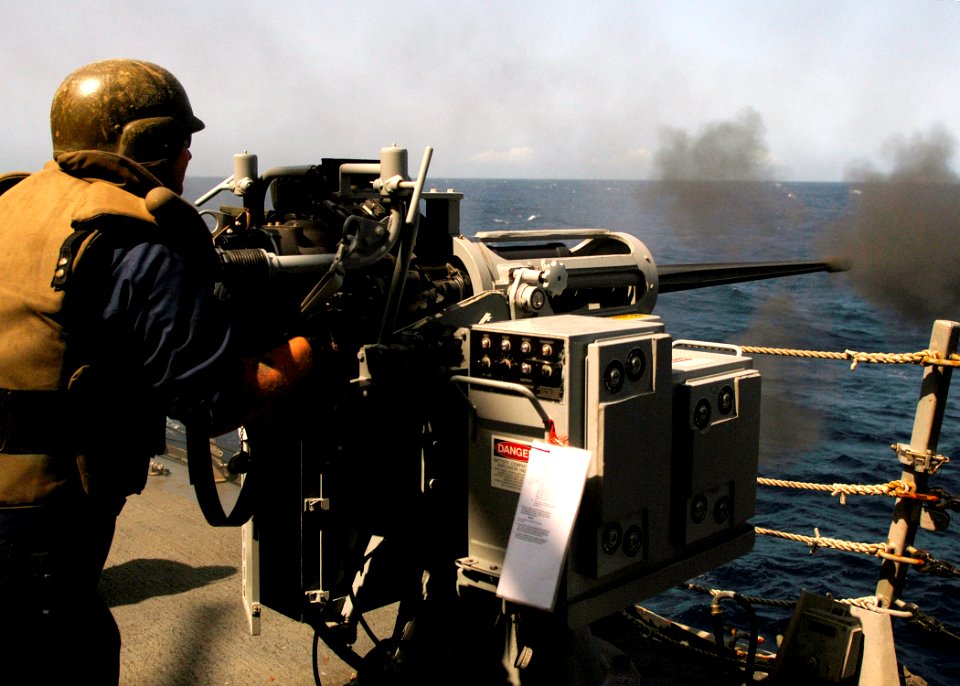 US Navy 070807-N-8132M-094 A Sailor fires a 25mm chain gun during a gun qualifications and small craft action team (SCAT) training exercise aboard the guided-missile destroyer USS Arleigh Burke (DDG 51)