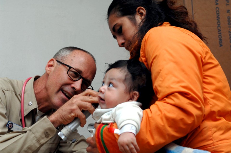 US Navy 070809-N-7088A-085 Cmdr. Craig Martin, attached to Military Sealift Command hospital ship USNS Comfort (T-AH 20), examines a baby at the Jose F. Sanchez Carrion School