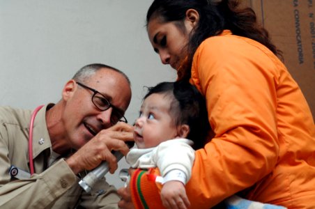 US Navy 070809-N-7088A-085 Cmdr. Craig Martin, attached to Military Sealift Command hospital ship USNS Comfort (T-AH 20), examines a baby at the Jose F. Sanchez Carrion School photo