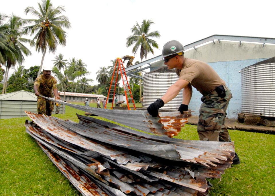 US Navy 070808-N-4267W-006 Steel Worker 3rd Class Doug Horrox attached to Naval Mobile Construction Battalion (NMCB) 7, and a member of the Papua New Guinea Defense Force (PNGDF) carry roofing