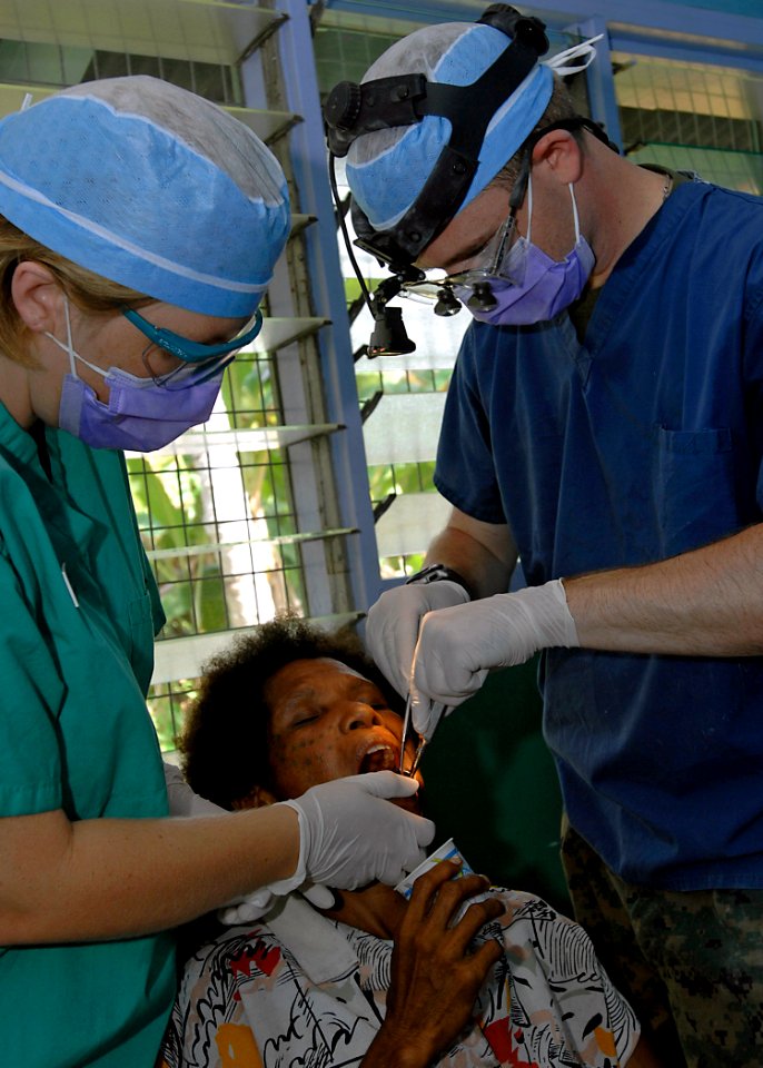 US Navy 070813-N-4954I-124 Lt. Kevin Haveman, attached to 11th Dental Company, extracts a tooth from a local patient with the help of dental assistant Sgt. Pattie-Lynne Powell, of the Canadian Forces Dental Services