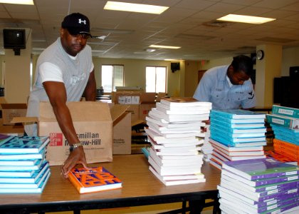 US Navy 070808-N-7427G-005 Information Systems Technician 1st Class Horace Wesley and Yeoman 3rd Class Tony Clofer organize books for the Belle Chasse Academy Charter School