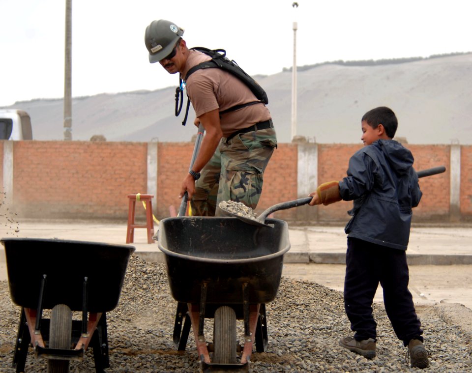 US Navy 070810-N-0194K-156 EO1 Manuel Gradillas, assigned to Construction Battalion Maintenance Unit (CBMU) 202, and a local boy, shovel rocks to mix into concrete at Miguel Grau School