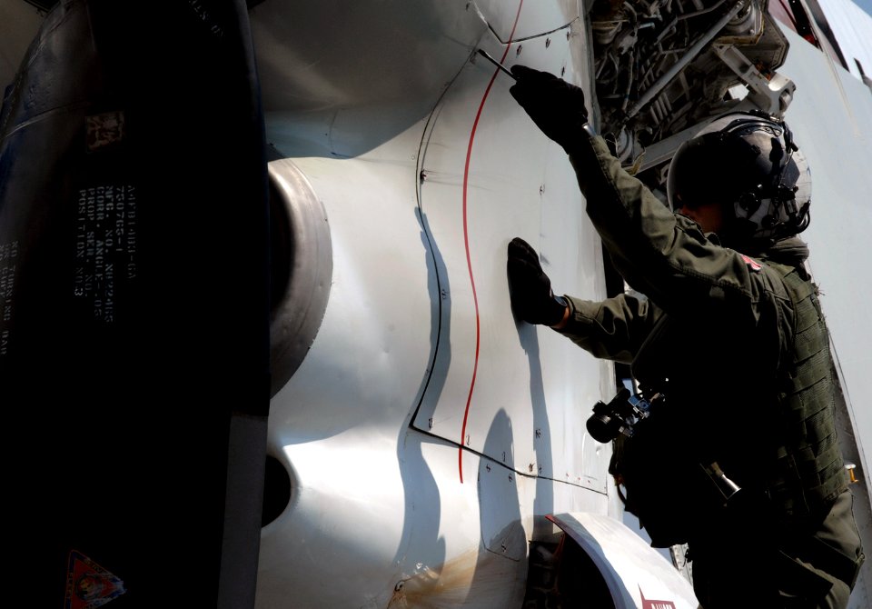 US Navy 070814-N-8923M-073 An air crewman loosens the screws of an engine cover to a C-2 Greyhound on the flight deck aboard Nimitz-class aircraft carrier USS Harry S. Truman (CVN 75)