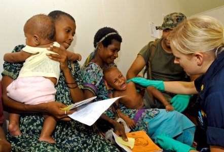 US Navy 070813-N-4954I-049 Ensign Stacy Syrstad, a nurse practitioner from Naval Medical Center San Diego, calms a child after a vaccination at a medical civil-assistance program (MEDCAP) at Ileg Clinic near Madang
