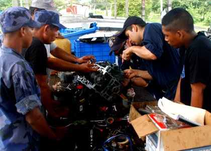 US Navy 070811-N-4021H-068 Sailors from USS Pearl Harbor (LSD 52) alongside Sailors from the Nicaraguan Navy, repair a small out-board engine while participating in a subject matter expert exchange during Partnership of the Ame