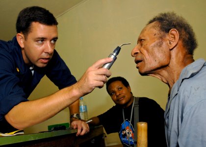 US Navy 070813-N-4954I-041 Lt. Cmdr. Matthew Behil examines a patient for cataracts while a volunteer translator stands by at Ileg Clinic near Madang