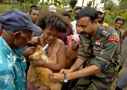 US Navy 070810-N-4954I-120 Lt. Col. Raveesh Chhajed, a veterinarian from the Indian Army, gives a family cat a rabies vaccination while onlookers gather to see the procedure photo