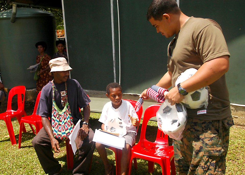 US Navy 070815-N-9421C-136 Hospitalman John Dahilig, attached to 3rd Medical Battalion, gives a young boy a soccer ball and flag while they wait to see medical personnel at Miak Health Clinic during a medical civic action progr