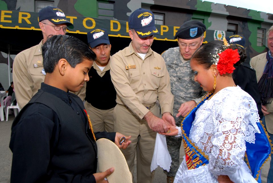 US Navy 070812-N-8704K-280 Capt. Bob Kapcio, mission commander for the Military Sealift Command (MSC) hospital ship USNS Comfort (T-AH 20), presents Alvako Coello and Lupita Carrion with commemorative mission coins after perfor