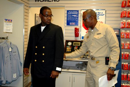 US Navy 070816-N-8102J-008 Chief petty officer (CPO) selectee, Gas Turbine System Electrical 1st Class Tremane Mason, tries on his new chief's uniform with the help from his sponsor, Senior Chief Sonar Technician Surface Brian